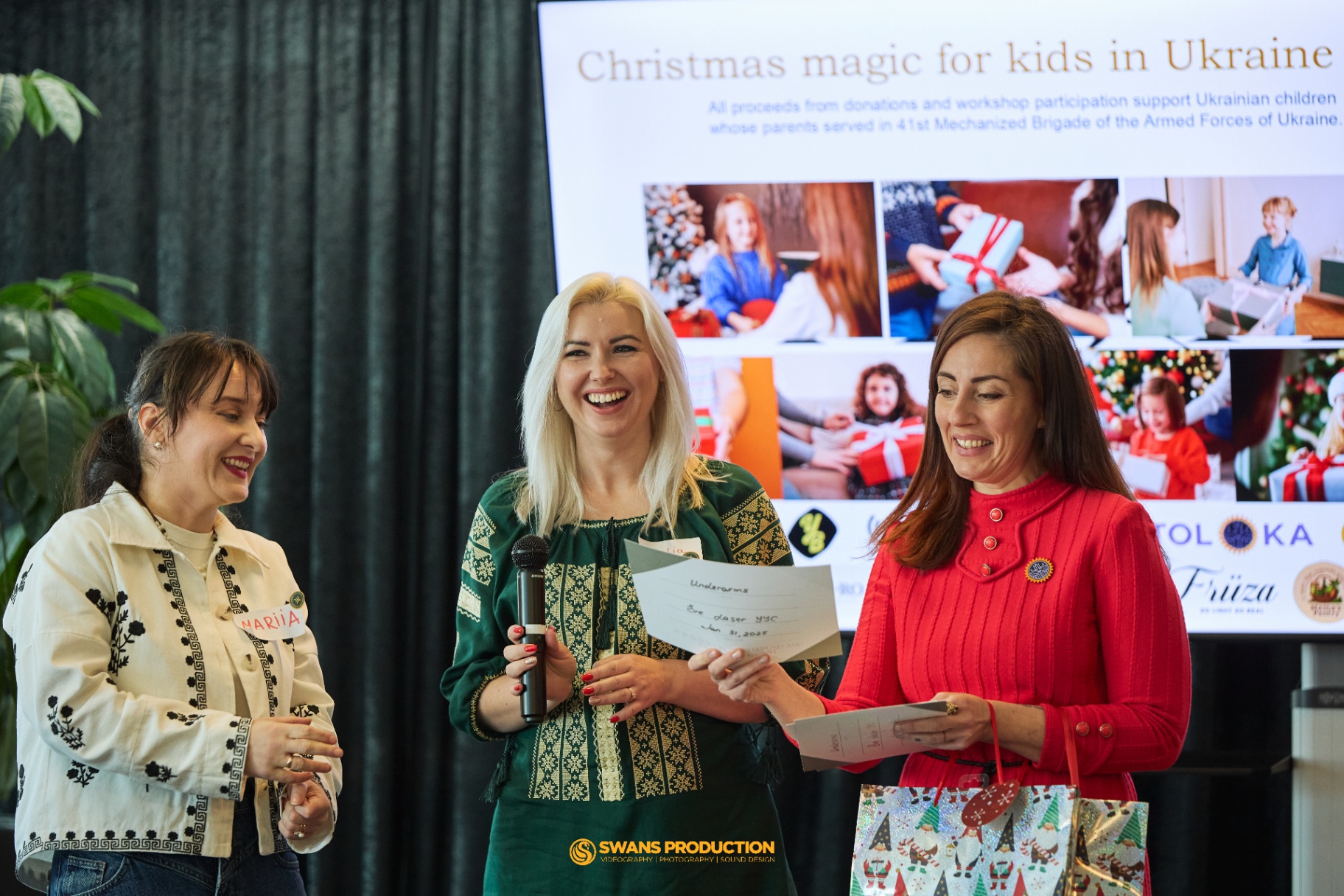 Organizers announcing silent auction winners on stage at the Christmas Magic for Kids in Ukraine event