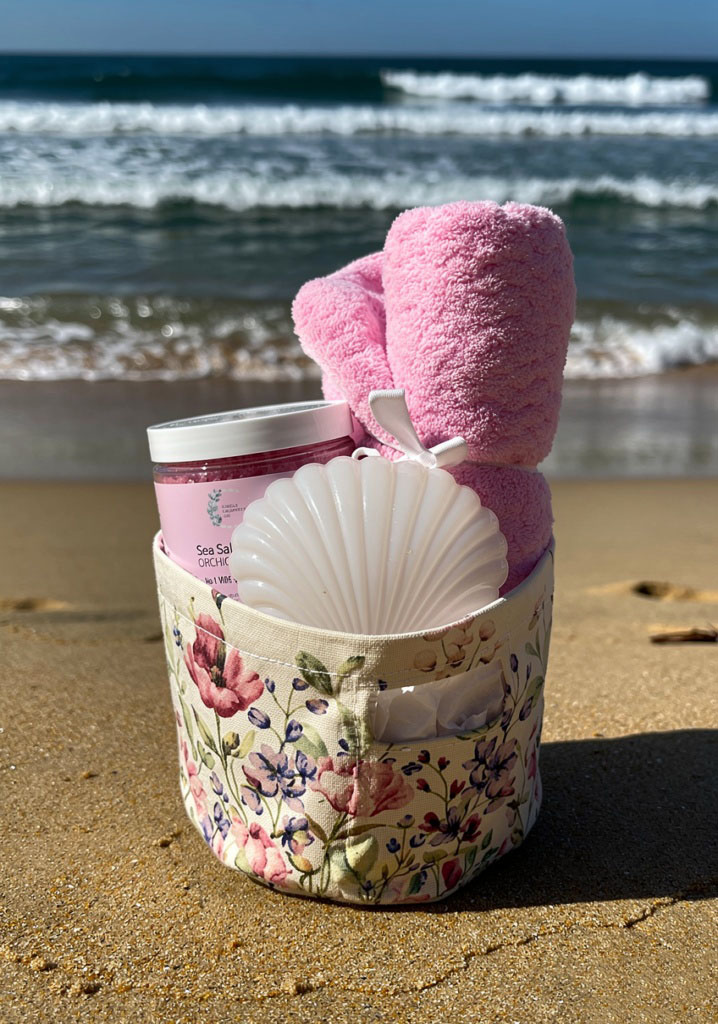 Pink towel and shell candle gift basket by the shoreline